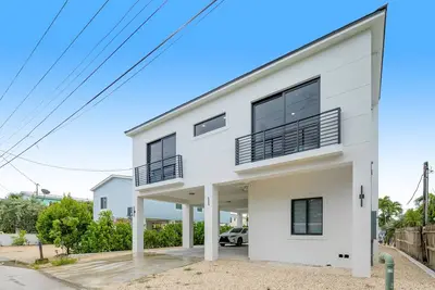 Modern canal-front home with a rooftop deck, open-concept interior, Ac, & W/D