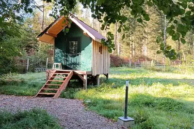 Image de La roulotte et sa petite maison attenante, dans un environnement forestier.