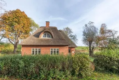 Image de reetgedecktes Ferienhaus mit Kachelofen