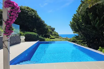 Image de villa moderne, lumineuse au milieu d'un jardin arboré avec magnifique vue mer