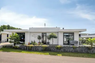 Image de Detached 6-person villa by the water with a cosy living room featuring a piano and fireplace, modern kitchen with cooking island, and a sunny garden with lounge set.