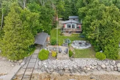 Image de Relax at this waterfront cottage on Colpoy’s Bay, perfect for up to 6 adults and 2 kids. Enjoy a private dock with tiki bar, firepit by the lake, boat access, and nearby trails. A peaceful, fully equipped retreat for your next vacation getaway.