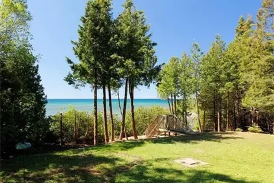 Image de Lakefront cottage near Tobermory with stunning water views, private beach, and cedar forest surroundings. Enjoy open-concept living, skylights, balconies, and peaceful trails—perfect for swimming, canoeing, and relaxing in nature.