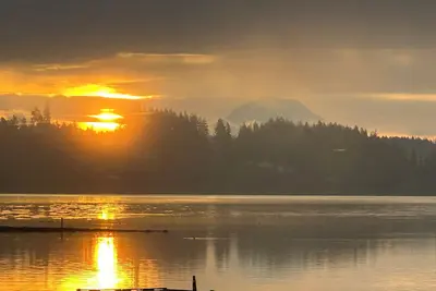 Image de Family-friendly waterfront home with sunrise views of Mt. Rainier. Enjoy zero-bank access, kayaks, bocce, cozy fire pit, and hot tub. Plenty of space with 2 kings, queen + trundle, and queen Murphy bed. A perfect Pnw escape minutes from Allyn.