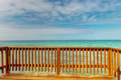 Image de Rustic overwater cabin with oceanfront deck, island kitchen & sea breeze views