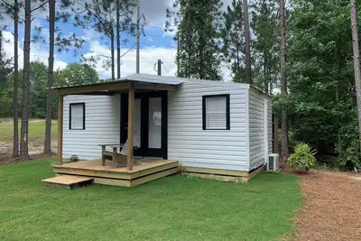 Modern tiny house with large outdoor area and grill.