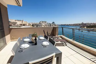 Image de Stylish penthouse in central Sliema on The Strand, Triq Ix-Xatt. Featuring 3 bedrooms, 2 bathrooms, a bright living area, and a large terrace with stunning views of Manuel Island and Valletta. Ideal for families, groups, or business stays.