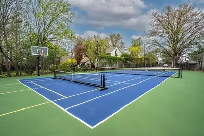 Image de A true hidden oasis with park-like grounds—your own private pickleball retreat. Enjoy a beautifully maintained setting with pickleball, tennis, and basketball surrounded by mature trees.