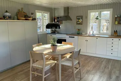 Image de Maison en bois noir entourée de bruyère près de l'eau