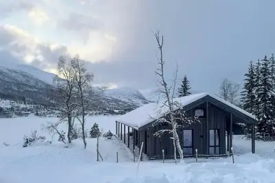 Image de Cabane au bord du lac Nysætervatnet, entourée de montagnes