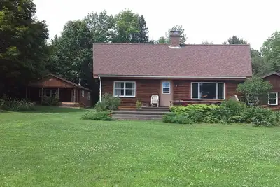 Image de Location de chalet dans les bois pittoresques du Maine avec des sentiers de raquette et une cheminée.