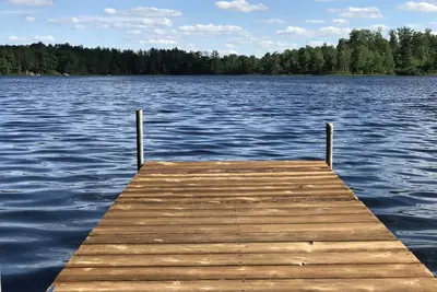 Image de cabane en rondins au bord du lac paisible, vierge sur une grande plage avec l'eau claire