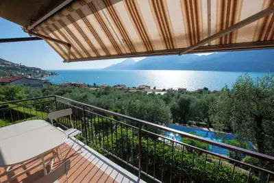 Image de balcon magnifique sur le lac avec une belle piscine et le jardin au milieu de palmiers et d'oliviers