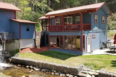 Image de Cabine rustique de deux étages sur le ruisseau avec pont couvert et. . .