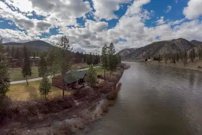 Image de Belle cabine nichée à droite sur la rivière Clark Fork entourée de montagnes.