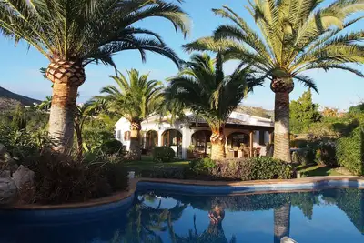 Image de Une maison de famille incroyable située dans des jardins tranquilles avec une forme libre bordée de palmiers