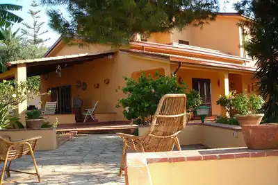 Image de Villa 'Le Plumbaco' avec une grande véranda et le jardin luxuriant. A 5 minutes de la mer