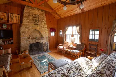 Image de Cabine / chalet classique avec grande véranda, cheminée en pierre, murs de pin noueux