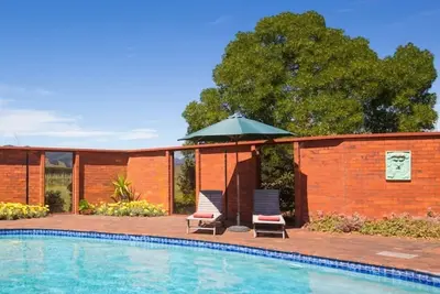 Image de Richmond Plains Vineyard Cottage avec piscine et bouteille de vin offerte.