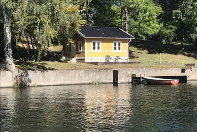 Image de Cottage avec terrasse en bois ensoleillée au bord de l'eau.