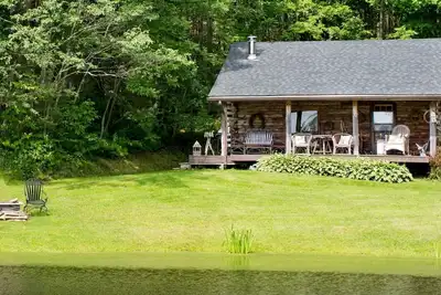 Image de Charmante cabane en rondins sur un étang privé niché dans les bois.
