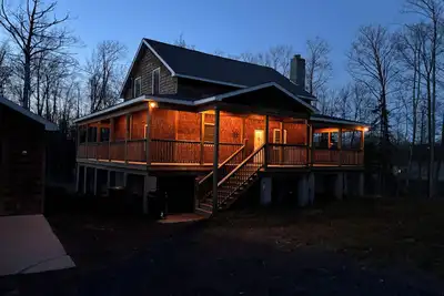 Image de Hot tub, piscine chauffée et bar extérieur sur un terrain spacieux et boisé.