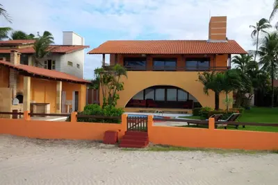 Image de Maison de plage avec piscine, terrasse ensoleillée et pied dans le sable.