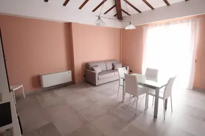 Image de appartement en bord de mer avec une grande terrasse avec un parasol et des chaises
