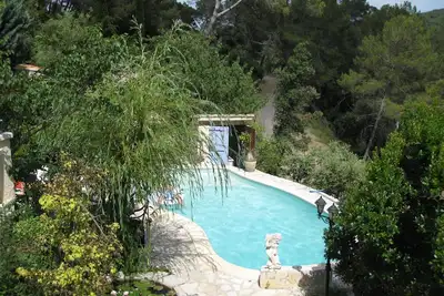 Image de Mas provençal en pierres naturelles dans une colline boisée avec piscine.