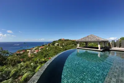 Image de Villa de luxe, piscine à débordement semi-circulaire, belvédère avec bar, coin salon avec banquette