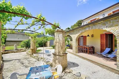 Image de Villa Deneria: Un cottage caractéristique et accueillant entouré de verdure.