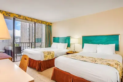 Image de 2 lits Queen confortables dans Waikiki Studio Suite avec piscine et barbecue