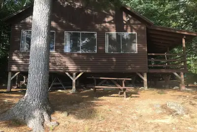 Image de Cabane rustique sur le lac Ambajejus avec plage de sable et vue sur la montagne