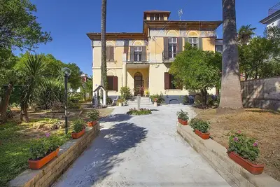 Image de Villa Liobe Grande: Un appartement confortable qui couvre tout le rez-de-chaussée d'une villa entourée de verdure.