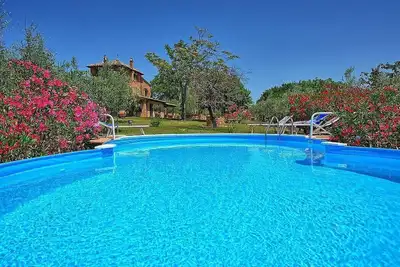 Image de Casa Moscatella: Une ancienne ferme caractéristique sur trois étages entourée de vignes et d'oliviers.