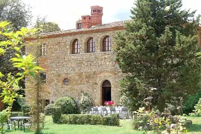 Image de Villa Doralicia B: Une villa historique caractéristique et accueillante de deux étages entourée de verdure.