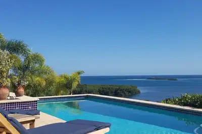 Image de Rainbow Paradise est un 4br / 3 moderne et magnifique sur le plan architectural. 5 Ba maison sur un terrain de 5 acres surplombant les baies de Manglar et Pela. Très isolée et privée. A / C dans Br, ventilateurs de plafond, cuisine complète, piscine ex.