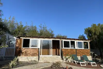 Image de Une belle oasis de maison en bois entourée de plantes et d'arbres.