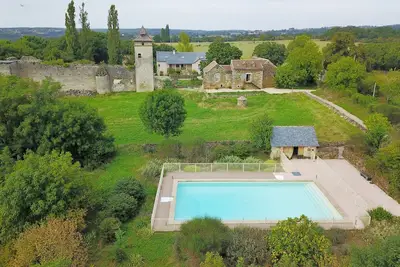 Image de Deux maisons avec une grande piscine à côté des ruines d'un château médiéval