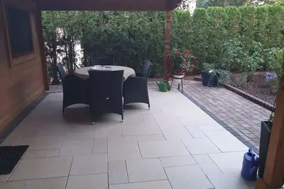 Un appartement de 2 chambres avec terrasse couverte dans le jardin.