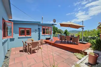 Image de Wintle93 - Stunning Views await you from the living areas and sunny deck of this traditional kiwi bach which has been tastefully modernised and is within a few minutes walk to both surf beach and estuary beaches. Pet friendly and Free wifi included!
