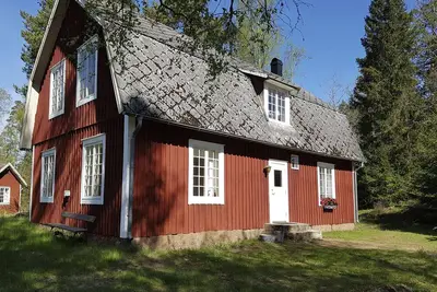 Image de Typical red and white holiday home surrounded by forest and lake
