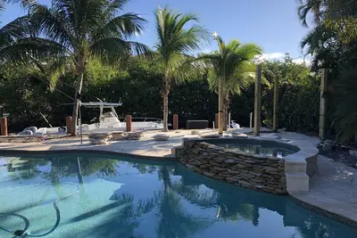 Image de Tropical waterfront oasis with private dock, pool, waterfall spa, tiki huts.