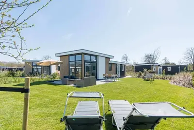 Image de Quel grand jardin! Ce chalet « style plage » est entièrement meublé avec un séjour avec un canapé c