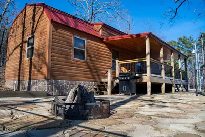 Image de Cabin featuring a vaulted ceiling, a large porch, and huge patio with fire pit.